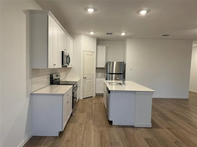 a kitchen with stainless steel appliances a sink stove and wooden floor