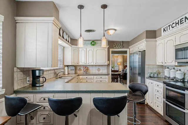 a kitchen with stainless steel appliances granite countertop a sink a stove a refrigerator cabinets and chairs