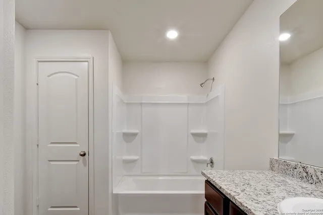 a bathroom with a granite countertop sink a toilet and shower