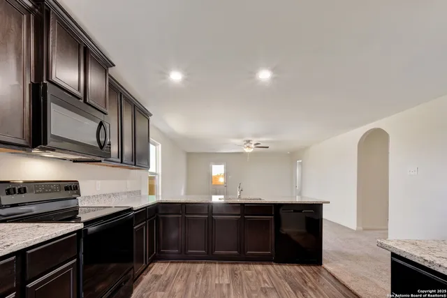 a kitchen with stainless steel appliances granite countertop a stove a sink and a microwave