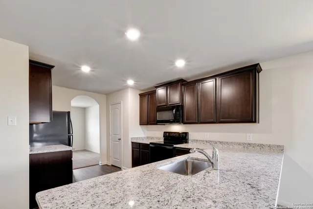 a kitchen with granite countertop stainless steel appliances wooden cabinets a refrigerator and a sink