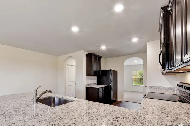 a kitchen with granite countertop a refrigerator and a sink