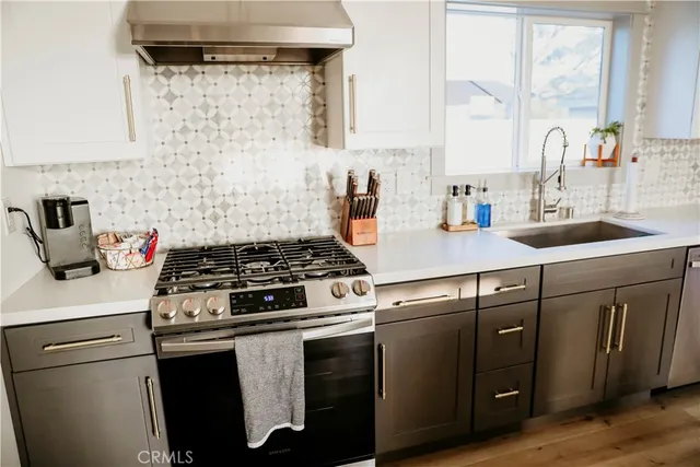 a kitchen with a sink a stove and white cabinets with wooden floor