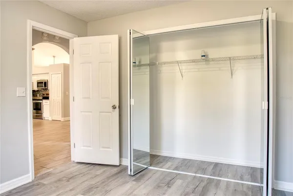 a view of an empty room with wooden floor and a bathroom