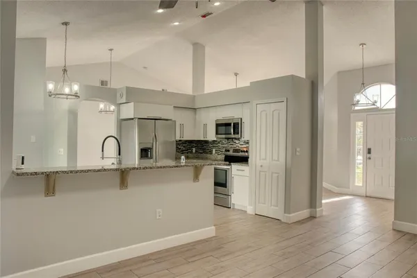 a kitchen with stainless steel appliances granite countertop a refrigerator a sink dishwasher a oven and white cabinets with wooden floor