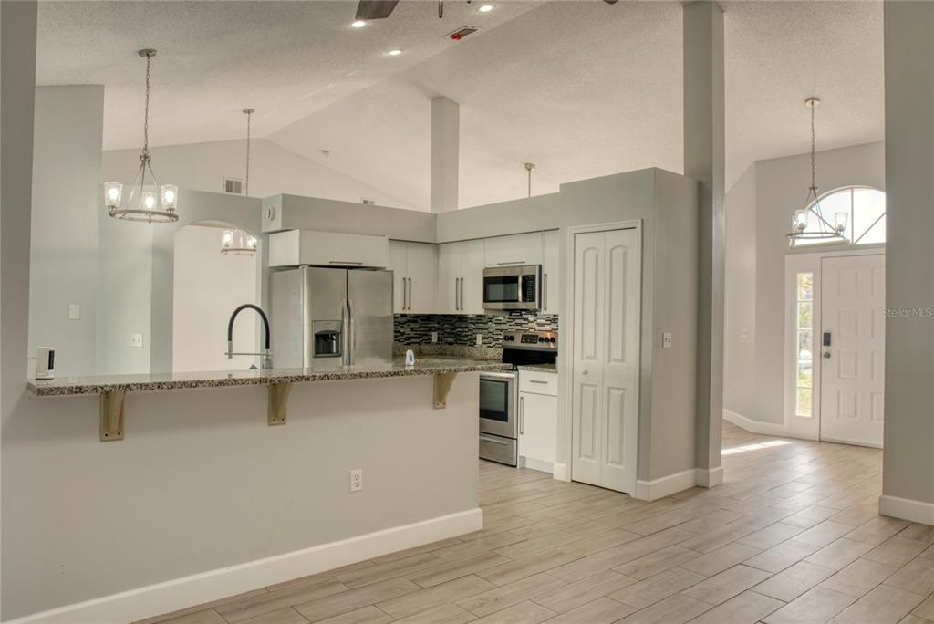 1447 Kingston Way Kissimmee, FL 34744 - Photo 7 of 24 a kitchen with stainless steel appliances granite countertop a refrigerator a sink dishwasher a oven and white cabinets with wooden floor