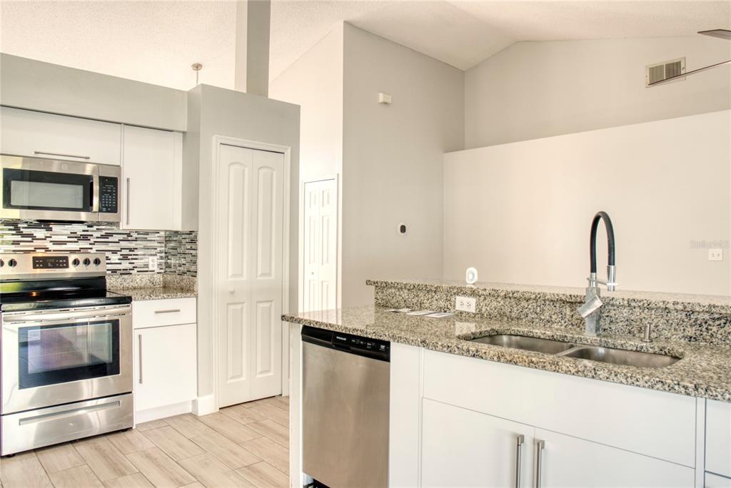 1447 Kingston Way Kissimmee, FL 34744 - Photo 9 of 24 a kitchen with granite countertop a sink and stainless steel appliances
