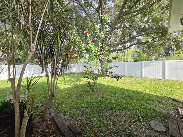 a view of backyard with table and chairs and large trees