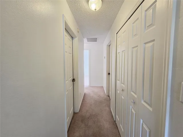 a view of a hallway with wooden floor and a bathroom