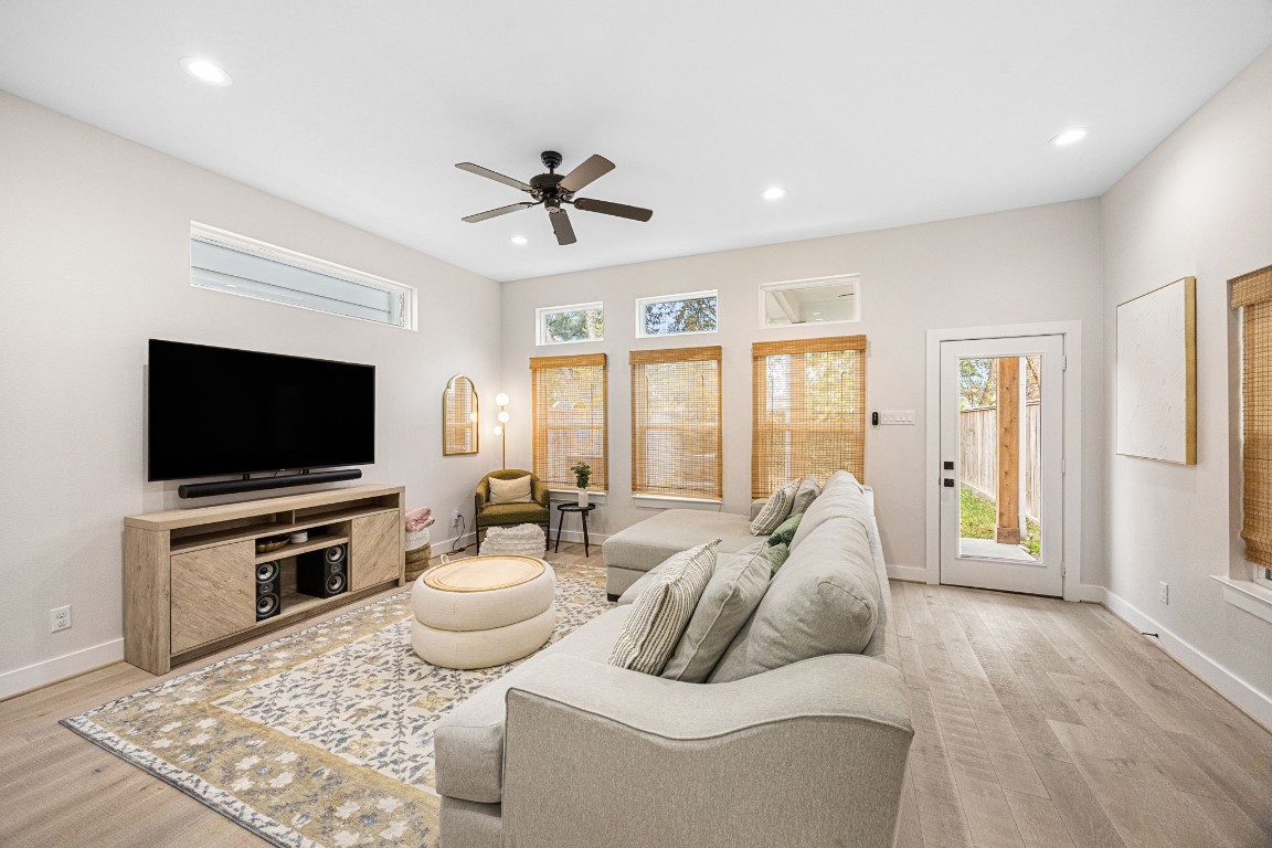 317 Sikes Street Houston, TX 77018 - Photo 15 of 30 Spacious living room enhanced by transom windows, complemented with custom window coverings for both privacy and aesthetic appeal. Back door provides convenient access to a covered patio, leading directly to a private and inviting backyard, perfect for relaxation and outdoor enjoyment.