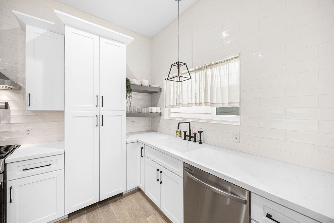 317 Sikes Street Houston, TX 77018 - Photo 5 of 30 Sleek modern kitchen with seamless white cabinetry, quartz counters, matte black fixtures, and subway tile backsplash – notice the hidden SECRET pantry behind the tall cabinet doors.