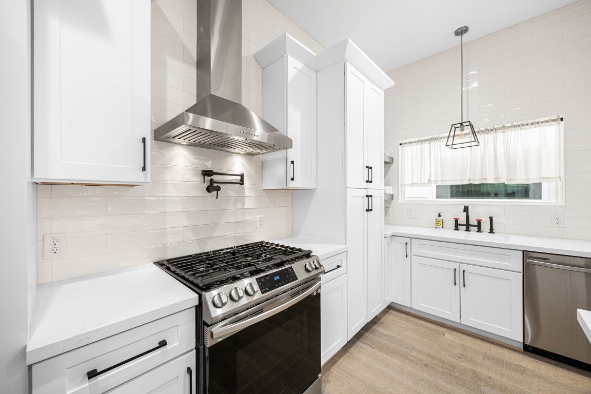 317 Sikes Street Houston, TX 77018 - Photo 8 of 30 Gas range, pot filler, subway tile backsplash, and sleek vent hood. Soft-close white shaker cabinets, matte black fixtures, quartz counters, and seamless design.