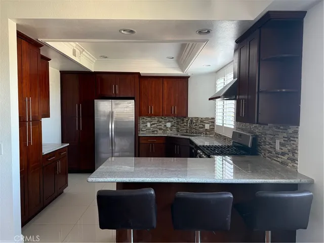 a kitchen with stainless steel appliances granite countertop a sink and a refrigerator