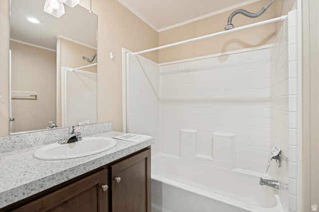 142 Cushing Way Layton, UT 84041 - Photo 11 of 15 Bathroom featuring a white bathtub and shower combination, dark wood-finish vanity with a white speckled countertop, and an oval undermount sink with a chrome faucet