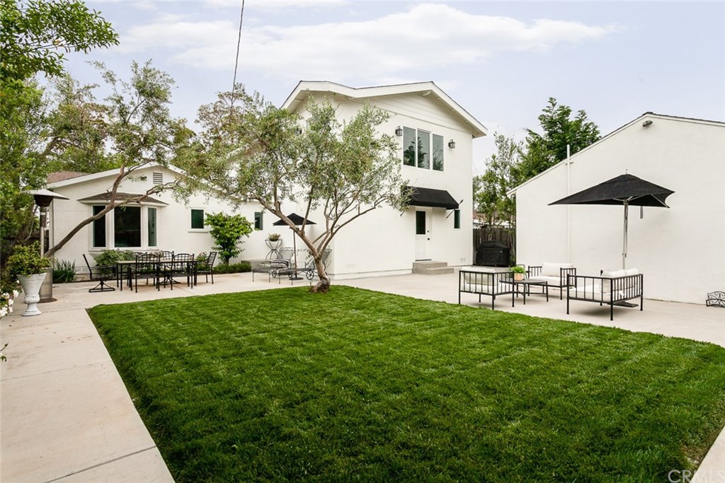 453 Broadway Costa Mesa, CA 92627 - Photo 31 of 39 a view of a white house with a big yard and table and chairs under an umbrella