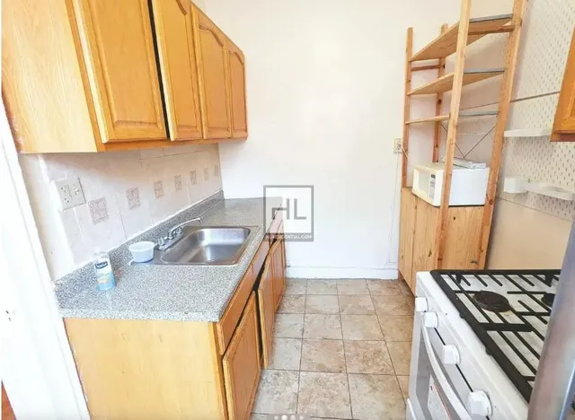 a kitchen with granite countertop a sink a stove and a wooden cabinets