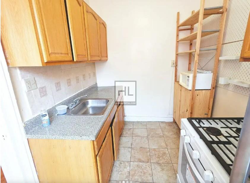 354 Rutland Road Brooklyn, NY 11225 - Photo 3 of 50 a kitchen with granite countertop a sink a stove and a wooden cabinets