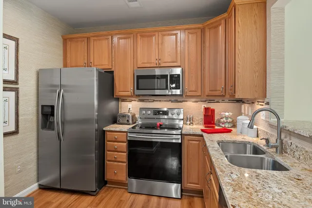a kitchen with granite countertop a sink and steel appliances