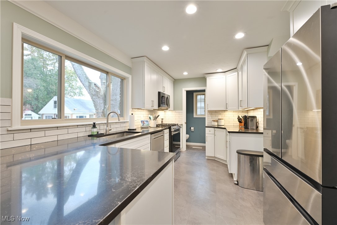 21887 Eaton Road Cleveland, OH 44126 - Photo 10 of 34 Kitchen with appliances with stainless steel finishes, backsplash, white cabinetry, dark stone countertops, and recessed lighting