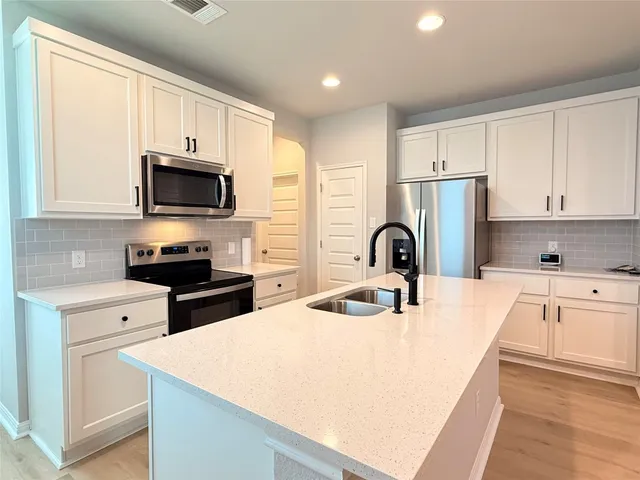 a kitchen with stainless steel appliances granite countertop a stove top oven a sink dishwasher and a refrigerator with wooden cabinets