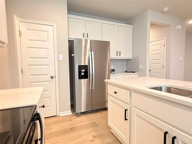 a kitchen with a refrigerator sink and cabinets