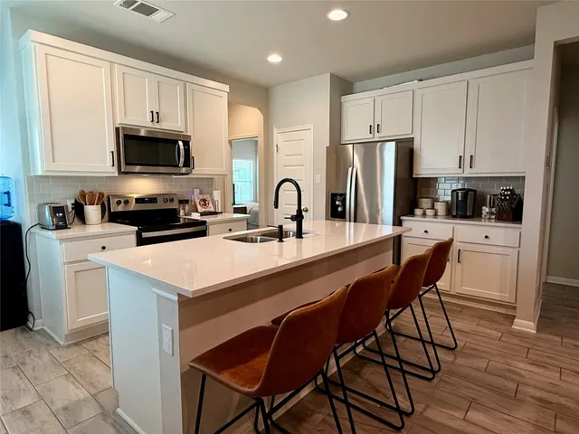 a kitchen with a sink a microwave a refrigerator and cabinets