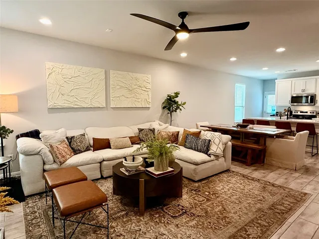 a living room with furniture kitchen view and a large window