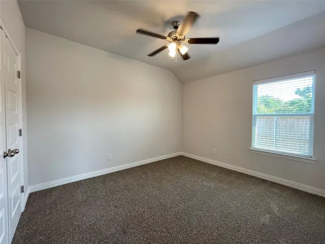 an empty room with a window and a fan