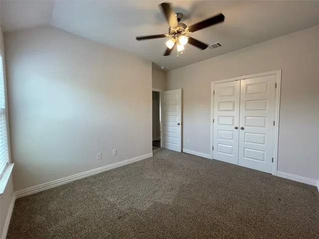 an empty room with windows and fan