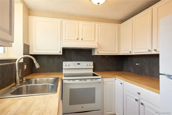a kitchen with granite countertop white cabinets and white appliances