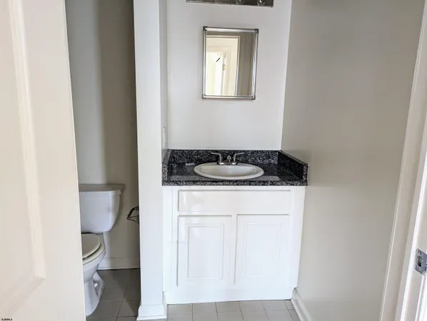 a bathroom with a granite countertop sink and a toilet