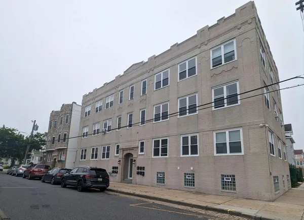 a city street lined with parked cars front of buildings