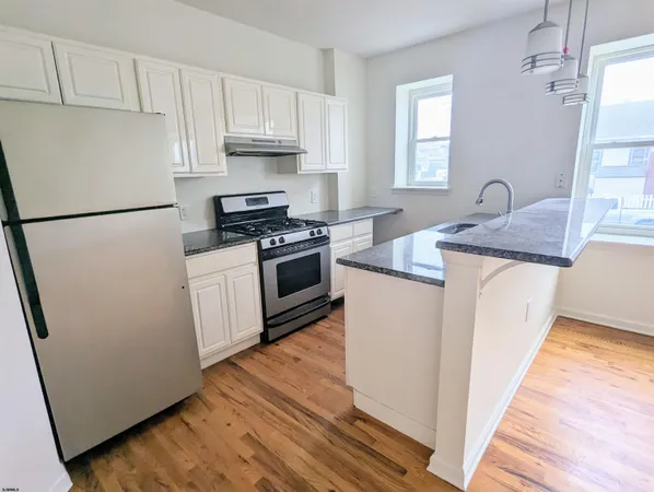 a kitchen with granite countertop white cabinets and white appliances