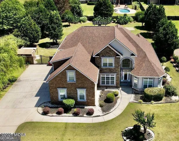 a aerial view of a house with swimming pool and large trees