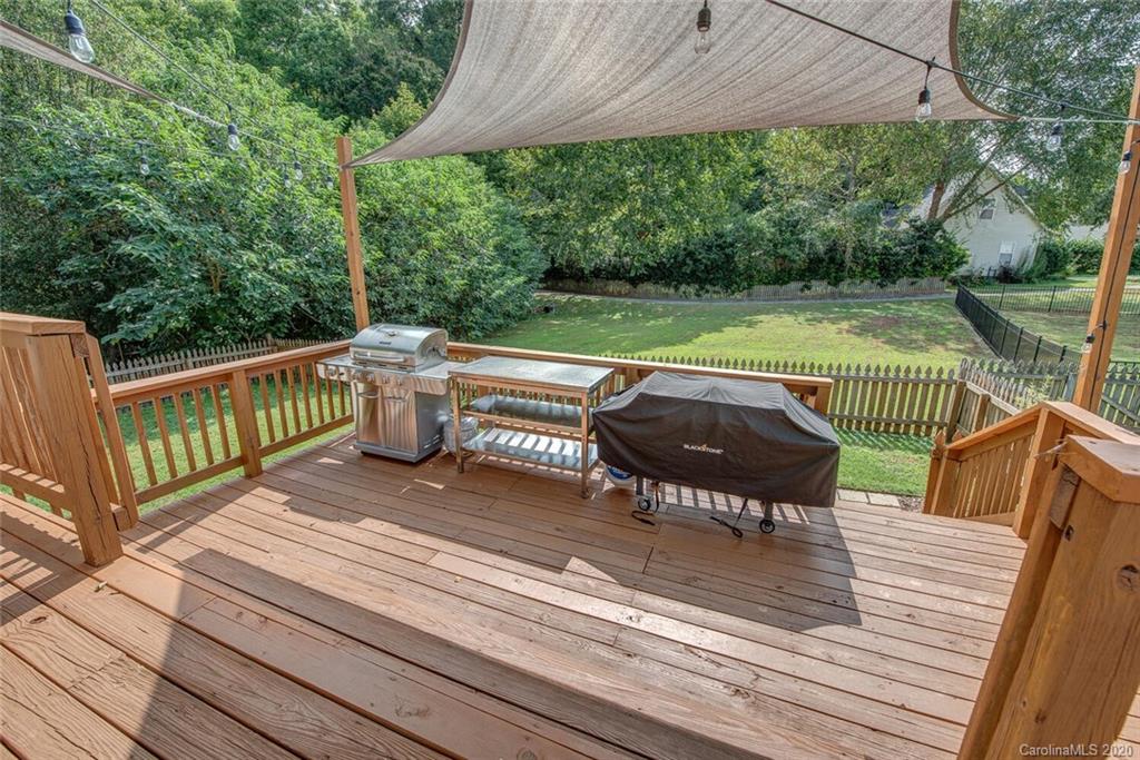 121 Pratt Street Belmont, NC 28012 - Photo 27 of 29 a view of a roof deck with table and chairs under an umbrella with wooden floor and fence