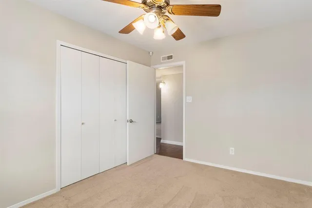 a view of an empty room and chandelier fan