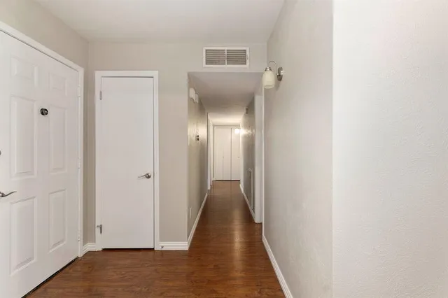 a view of a hallway with wooden floor and a bathroom