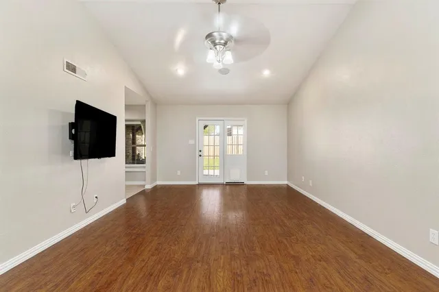 a view of an empty room with wooden floor and a window