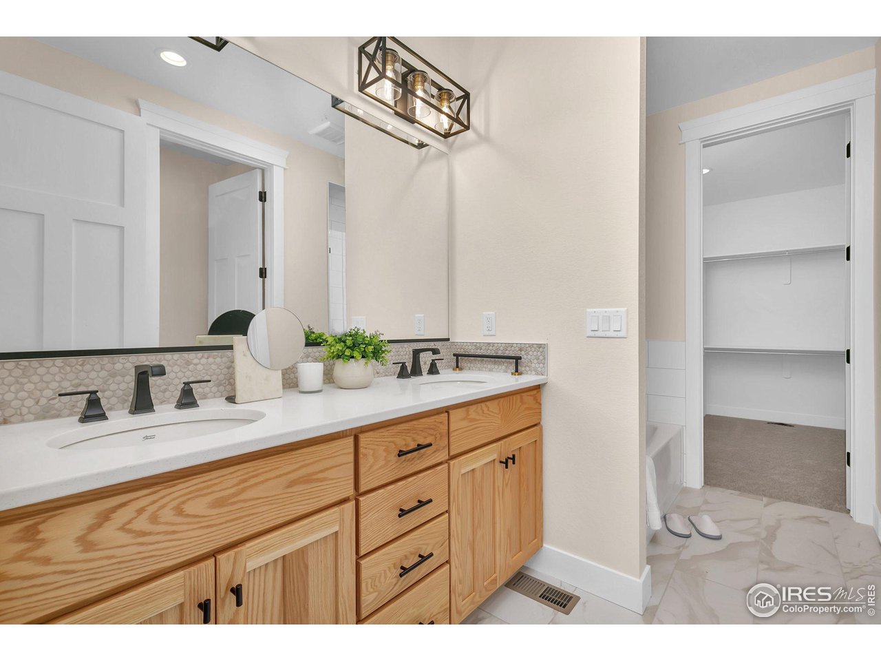 5722 West 3rd Street Greeley, CO 80634 - Photo 15 of 30 The primary ensuite, featuring dual vanities, a full-width mirror, porcelain flooring, & porcelain vanity sinks