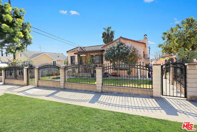 a view of a house with a small yard and a large tree