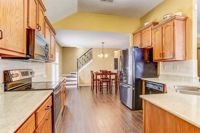 a kitchen with stainless steel appliances granite countertop a refrigerator a stove top oven a sink and dishwasher