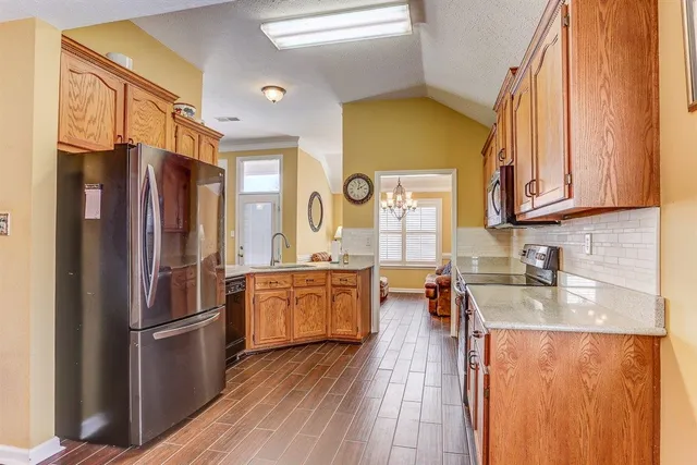 a kitchen with stainless steel appliances granite countertop a refrigerator a oven a sink dishwasher and wooden cabinets with wooden floor