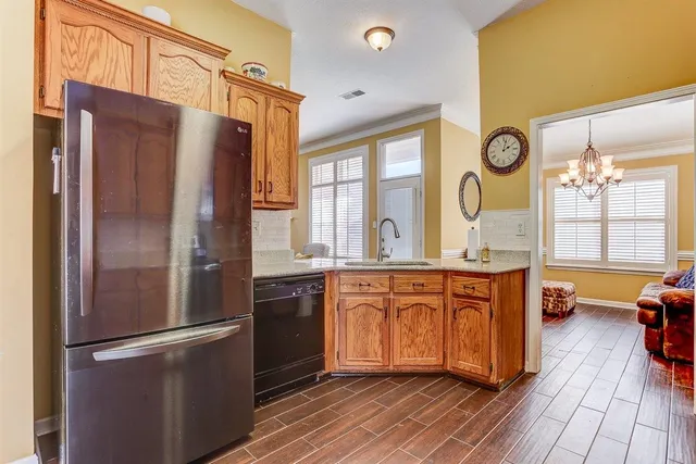 a kitchen with stainless steel appliances granite countertop a refrigerator a oven a sink and dishwasher with wooden floor