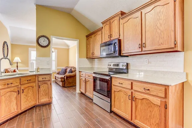 a kitchen with stainless steel appliances granite countertop a sink dishwasher stove and white cabinets with wooden floor