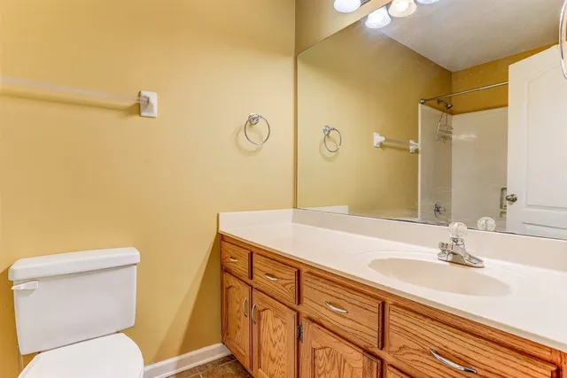 a bathroom with a granite countertop sink mirror vanity and toilet