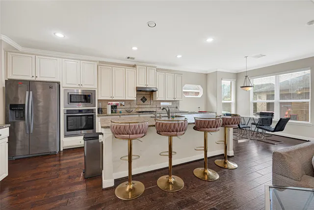 a kitchen with a refrigerator a stove a sink and a dining table with wooden floor