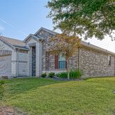 a view of a house with brick walls and a yard with large tree