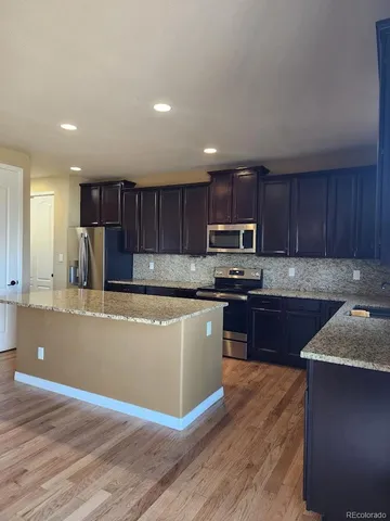 a kitchen with granite countertop wooden floors stainless steel appliances and cabinets