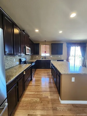 a large kitchen with stainless steel appliances granite countertop a stove and large cabinets