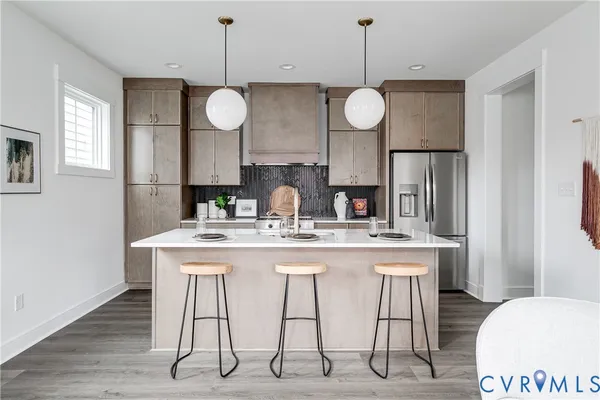 a kitchen with stainless steel appliances granite countertop a sink a refrigerator a stove a dining table and chairs with wooden floor